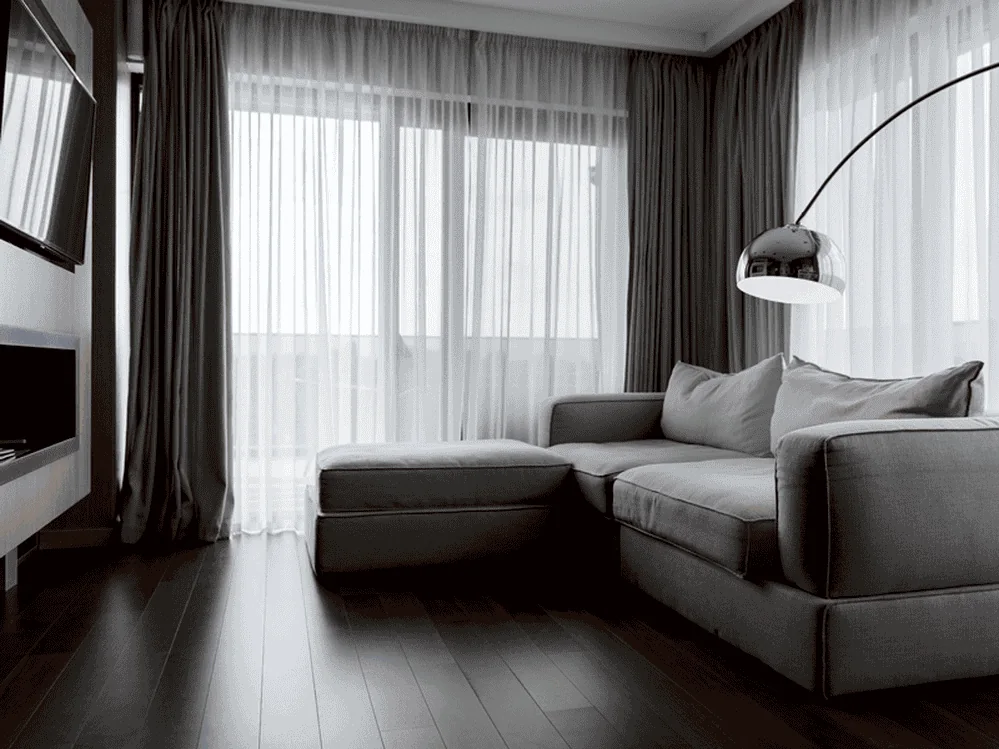 Sala com cortinas claras e sofá cinza